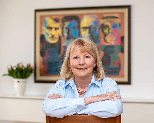 Christina Schmid-Preissler in heller Bluse vor einem Gemälde